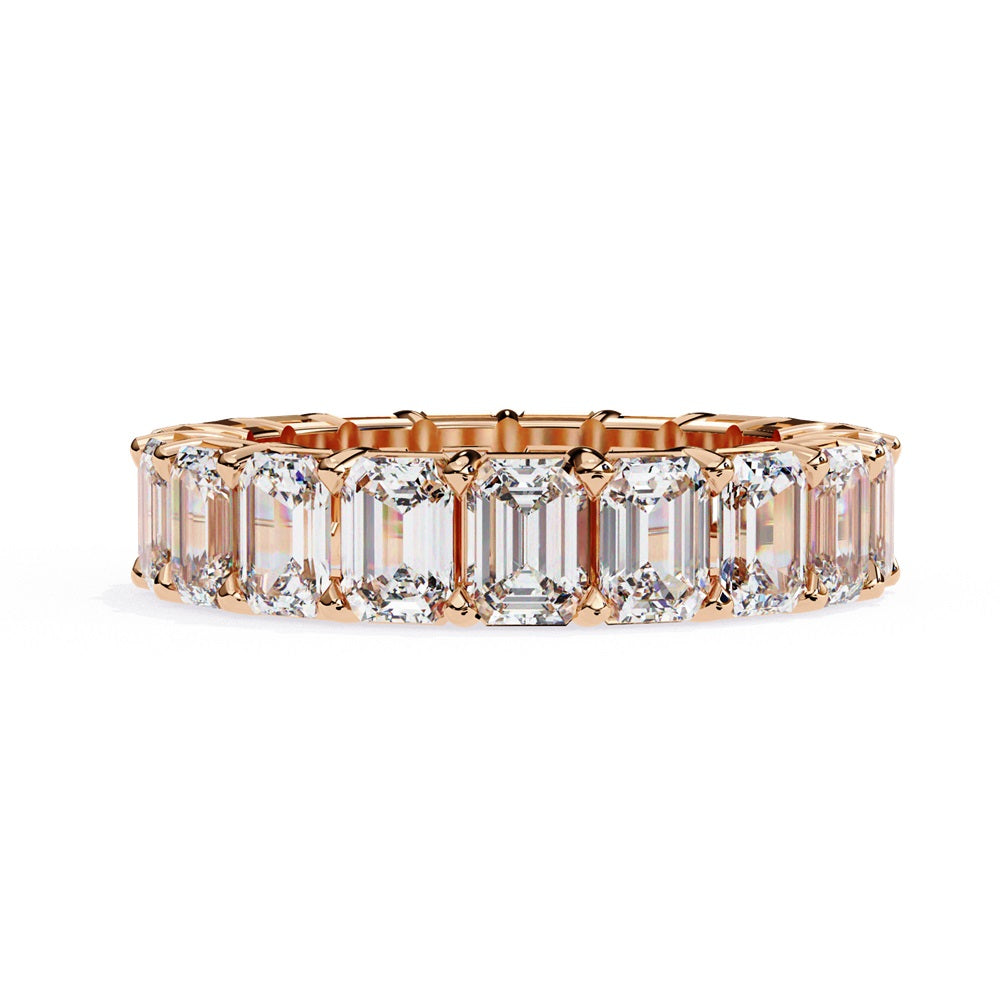 The Niraa Emerald Cut Diamond Eternity Band is a luxurious gold ring that features a continuous row of large prong-set emerald-cut diamonds, showcasing their brilliance and symmetry.