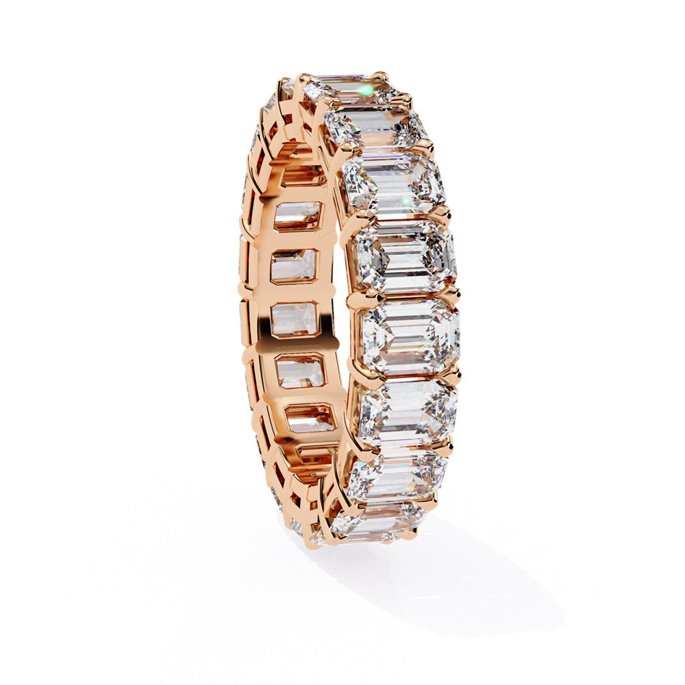 The Niraa Emerald Cut Diamond Eternity Band is a luxurious gold ring that features a continuous row of large prong-set emerald-cut diamonds, showcasing their brilliance and symmetry.