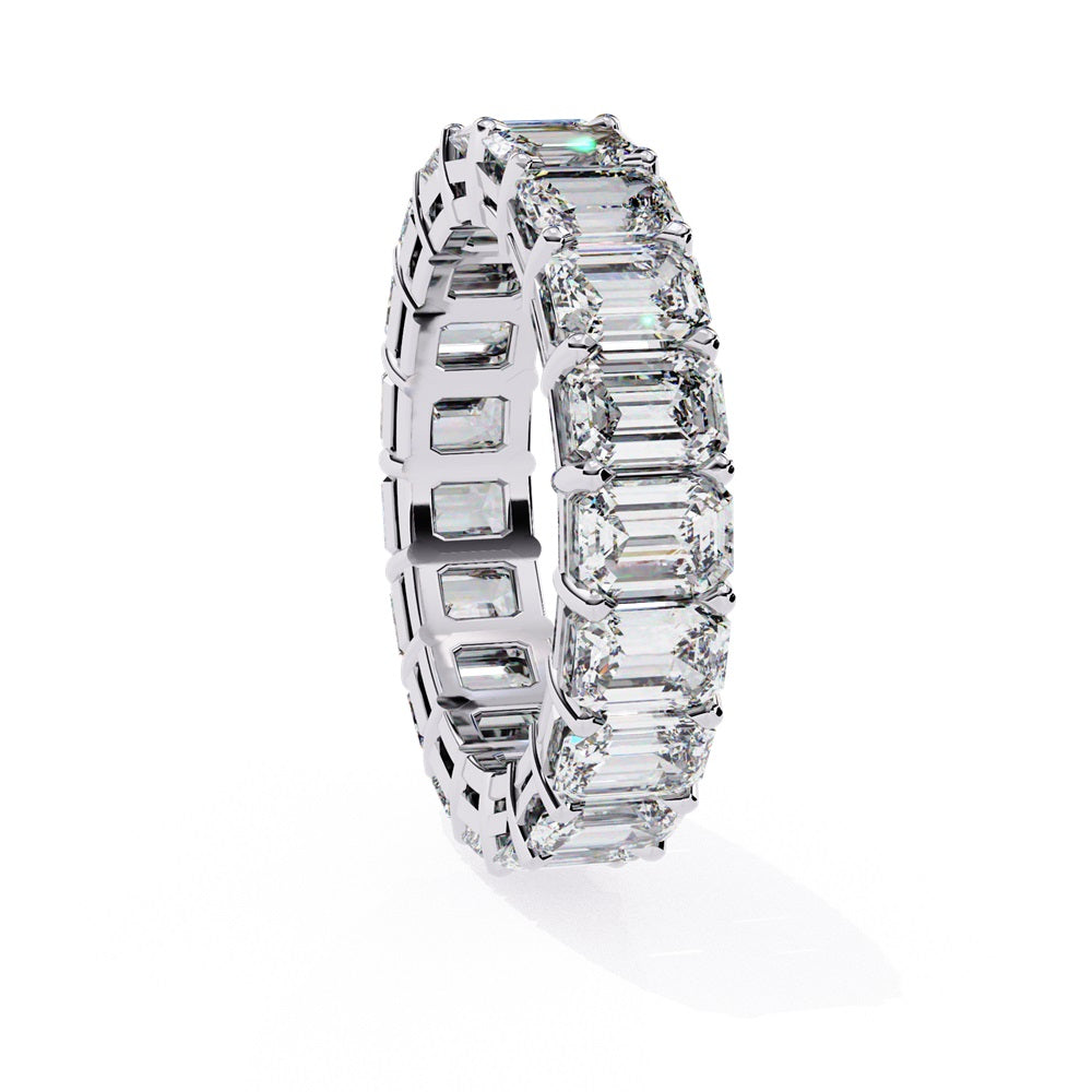 The Niraa Emerald Cut Diamond Eternity Band is a luxurious gold ring that features a continuous row of large prong-set emerald-cut diamonds, showcasing their brilliance and symmetry.