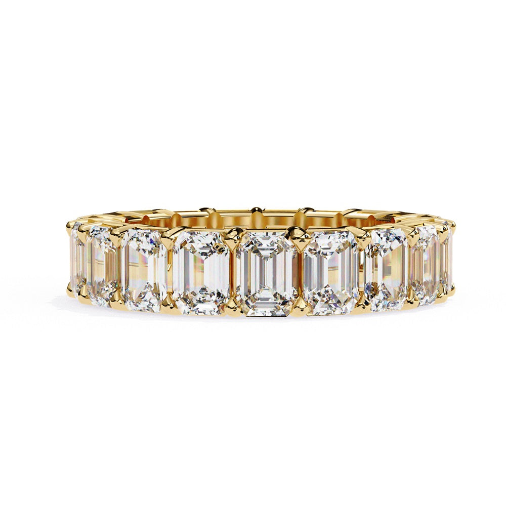 The Niraa Emerald Cut Diamond Eternity Band is a luxurious gold ring that features a continuous row of large prong-set emerald-cut diamonds, showcasing their brilliance and symmetry.