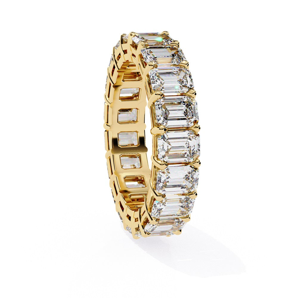 The Niraa Emerald Cut Diamond Eternity Band is a luxurious gold ring that features a continuous row of large prong-set emerald-cut diamonds, showcasing their brilliance and symmetry.