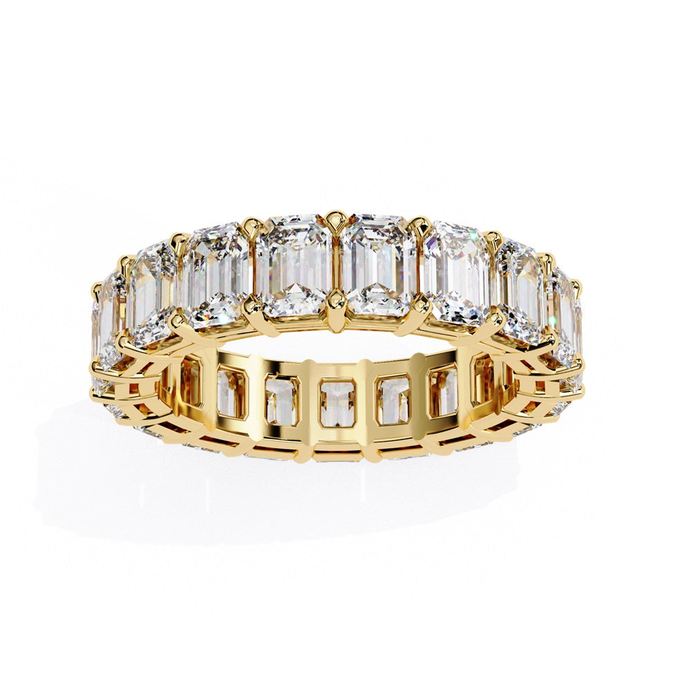 The Niraa Emerald Cut Diamond Eternity Band is a luxurious gold ring that features a continuous row of large prong-set emerald-cut diamonds, showcasing their brilliance and symmetry.