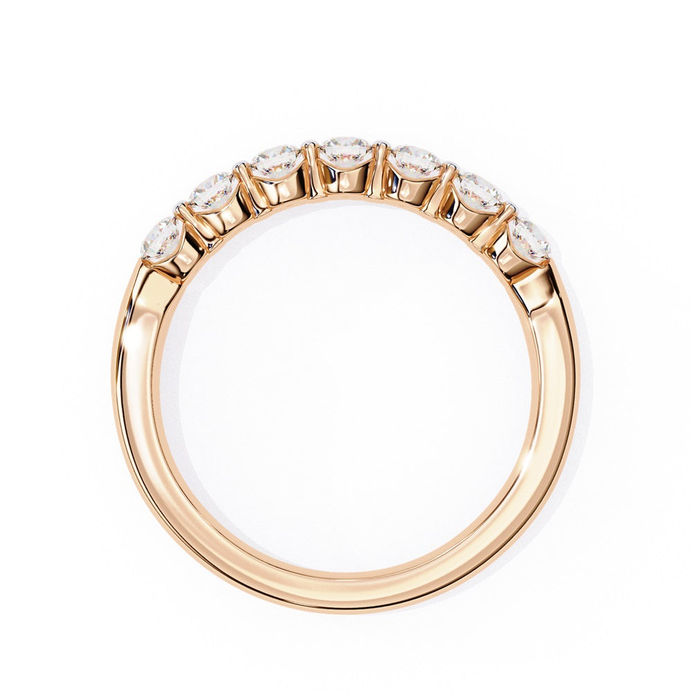The Niraa Seven Star Diamond Band is a luxurious gold ring with seven round, evenly spaced, sparkling diamonds, offering elegance and sophistication. The exquisite accessory is beautifully showcased on a plain white background.