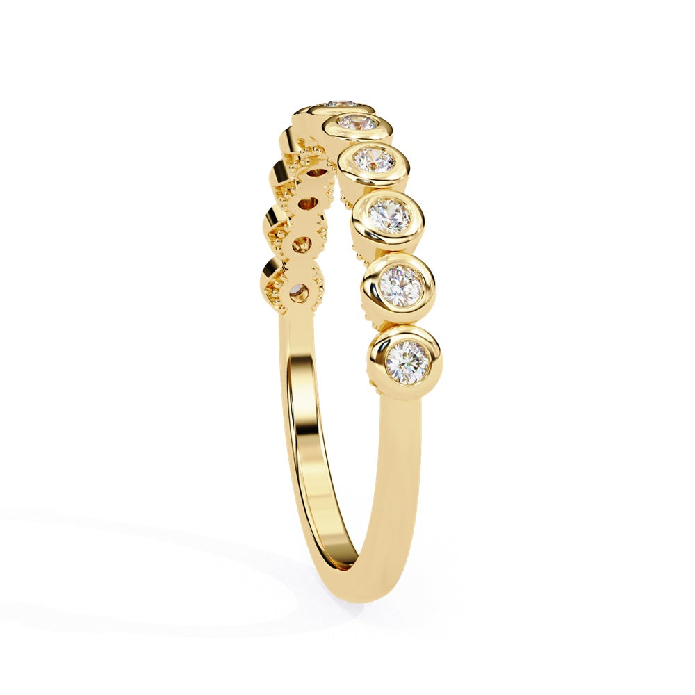 The Basel Diamond Band by Niraa is a luxurious gold ring featuring small, round diamonds set in individual bezels for a continuous sparkling effect.