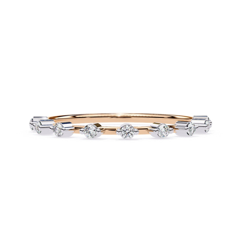 The Sunrise Diamond Band by Niraa is a luxurious gold ring featuring an elegant alternating pattern of round and baguette-cut diamonds set in a row, beautifully showcasing the sparkling gemstones against its smooth surface.