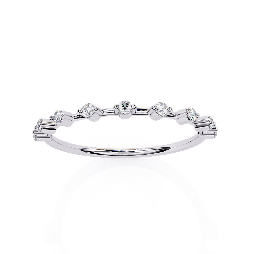 The Sunrise Diamond Band by Niraa is a luxurious gold ring featuring an elegant alternating pattern of round and baguette-cut diamonds set in a row, beautifully showcasing the sparkling gemstones against its smooth surface.