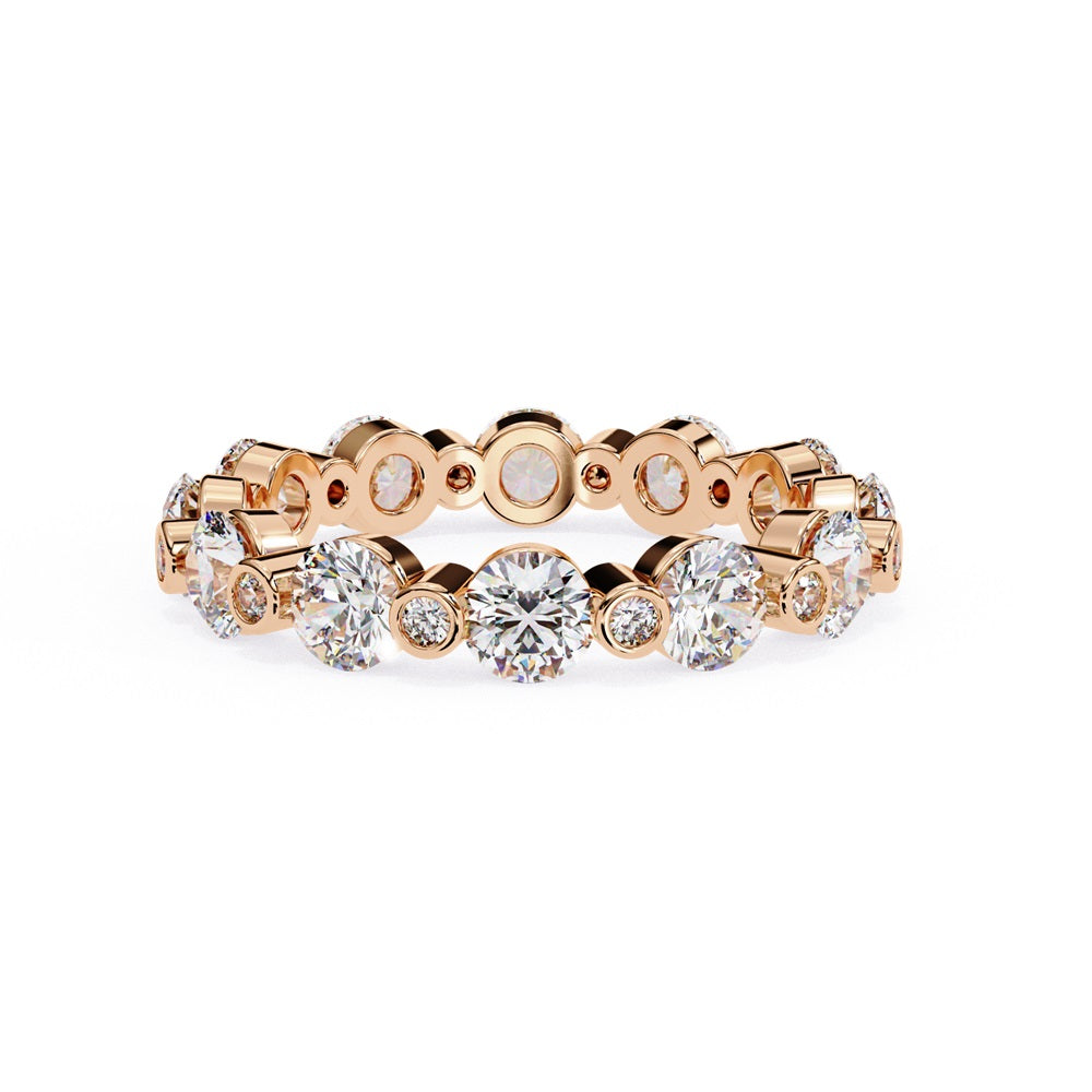 The Niraa Dazzling Diamond Eternity Band, adorned with alternating large and small round diamonds encircling the gold band, embodies luxury through its symmetrical design, showcasing brilliance and elegance in perfect harmony.