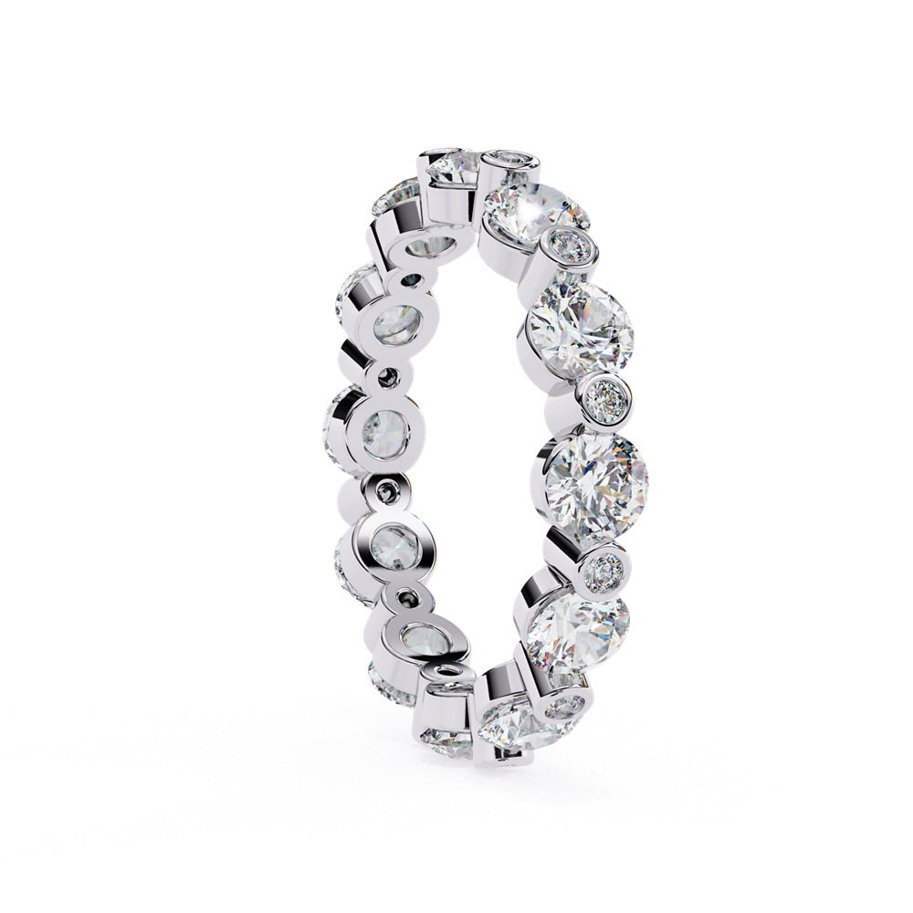 The Niraa Dazzling Diamond Eternity Band, adorned with alternating large and small round diamonds encircling the gold band, embodies luxury through its symmetrical design, showcasing brilliance and elegance in perfect harmony.