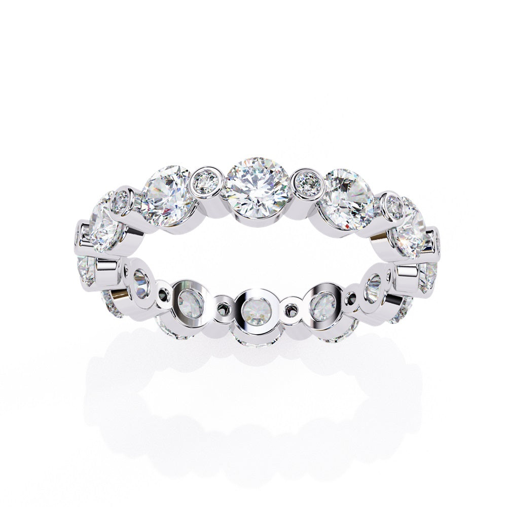 The Niraa Dazzling Diamond Eternity Band, adorned with alternating large and small round diamonds encircling the gold band, embodies luxury through its symmetrical design, showcasing brilliance and elegance in perfect harmony.