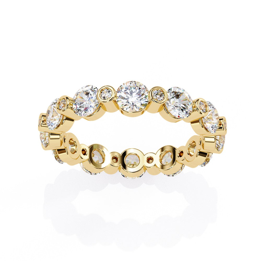 The Niraa Dazzling Diamond Eternity Band, adorned with alternating large and small round diamonds encircling the gold band, embodies luxury through its symmetrical design, showcasing brilliance and elegance in perfect harmony.