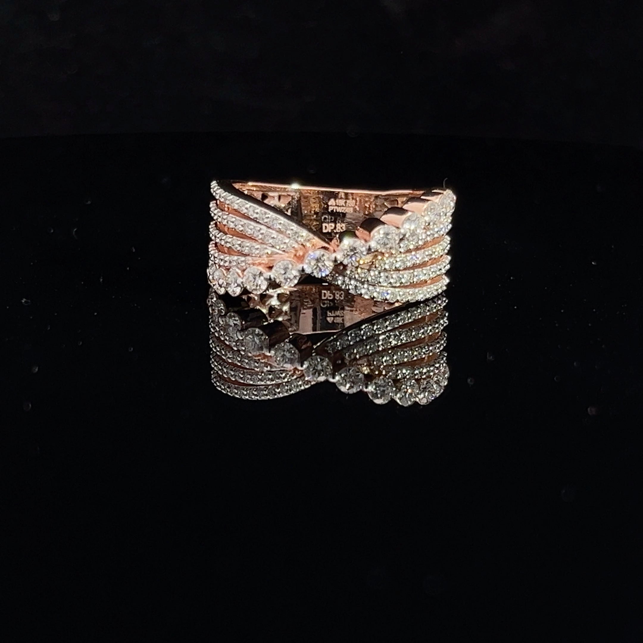 The Trinity Diamond Ladies Ring by Niraa features intricate interwoven bands that glisten on a dark reflective surface. The gold design, adorned with multiple small diamonds, exudes the allure of luxury.